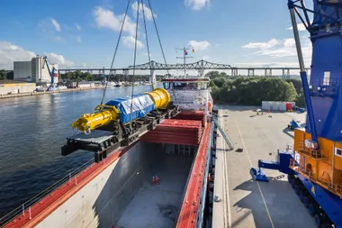 Ein Schiff wird am Hafen durch einen Kran mit Schwerlastgut beladen